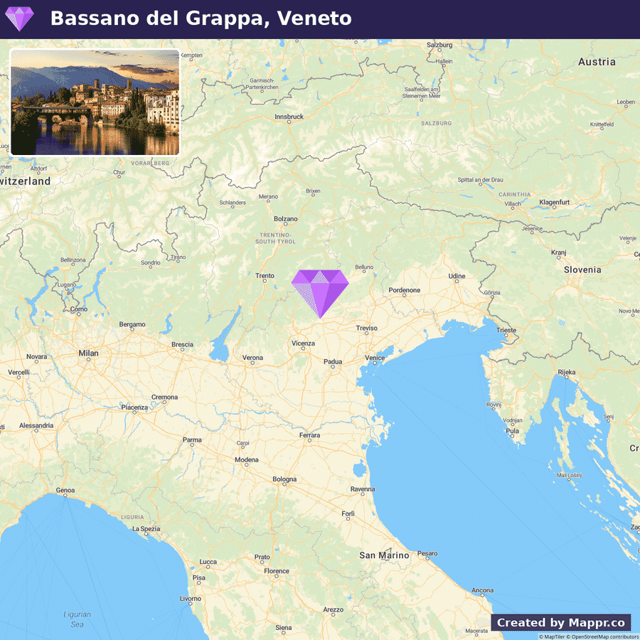 A map showing the location of Bassano Del Grappa in the Veneto region of Italy with a photo inset of the town at dusk, featuring illuminated buildings along the riverbank.