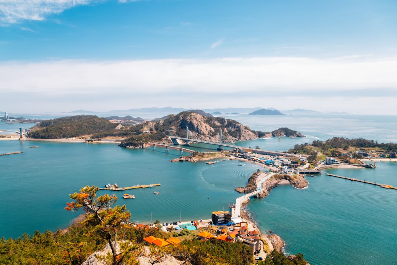 A scenic view of a coastal area with an expansive bridge crossing blue waters, connecting multiple i