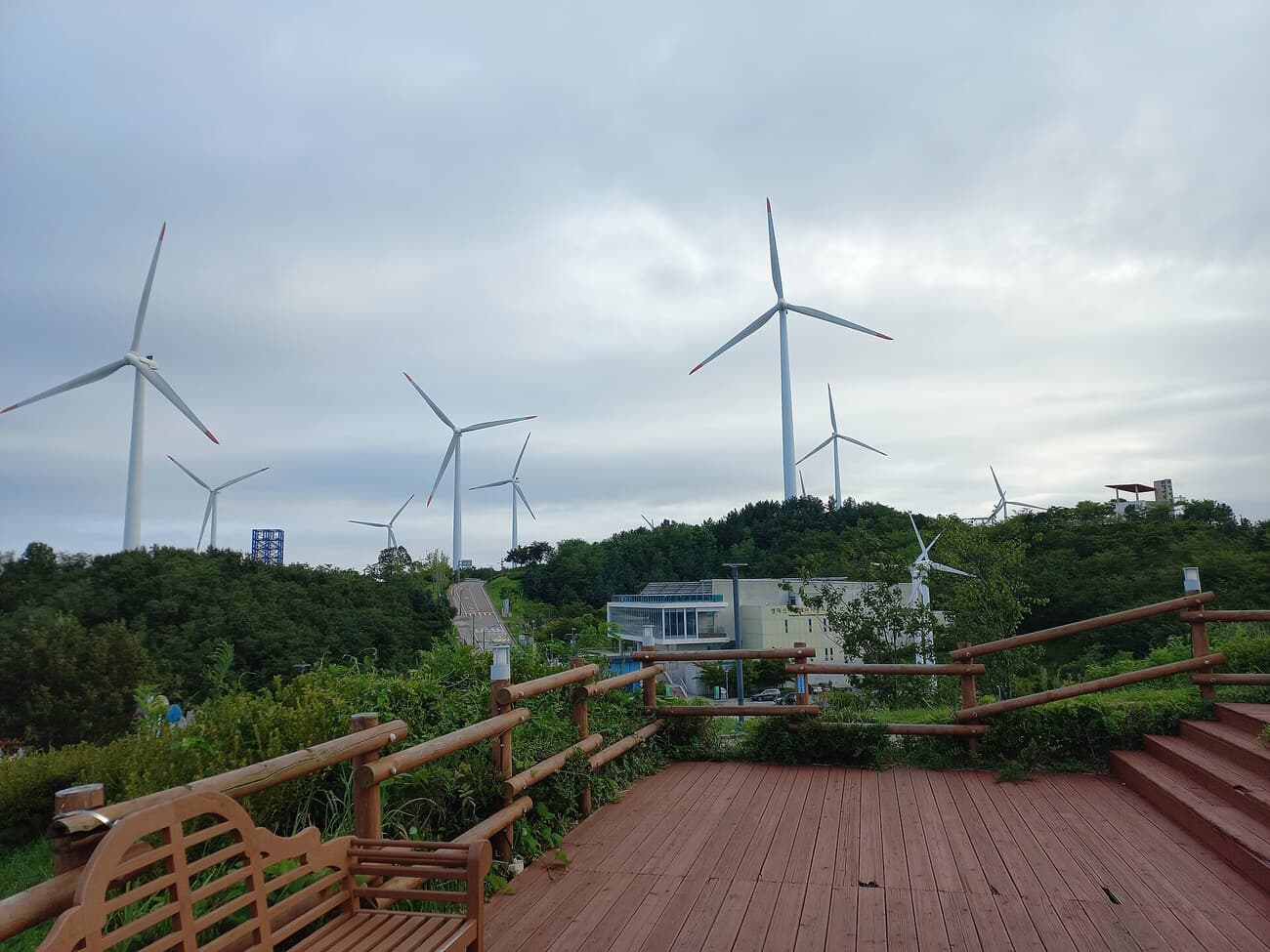 Wind turbines rising over the wooden observation decks of Yeongdeok's hilltop wind farm near Haemaji Park