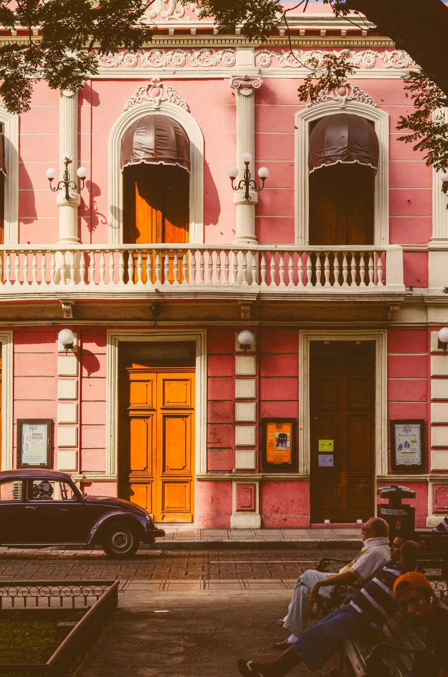 A pastel-pink colonial facade with orange doors on a quiet street in Mérida — the Yucatán capital regularly ranked among the safest cities in the Americas.