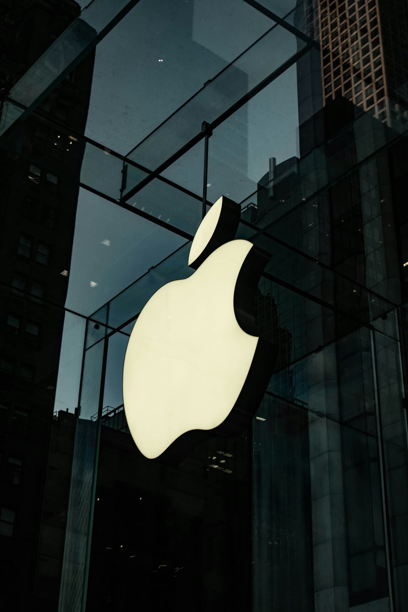 Appleโs Fifth Avenue store glass cube in New York, with the illuminated logo visible from the plaza
