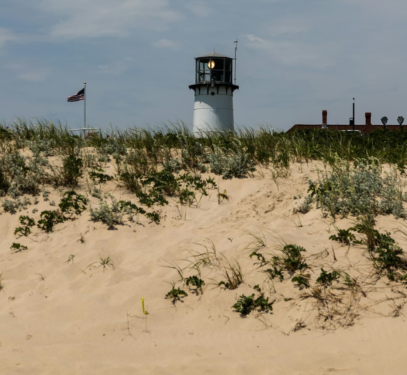 A lighthouse peeks over wind-combed dunes near Chatham on Cape Cod, Massachusetts