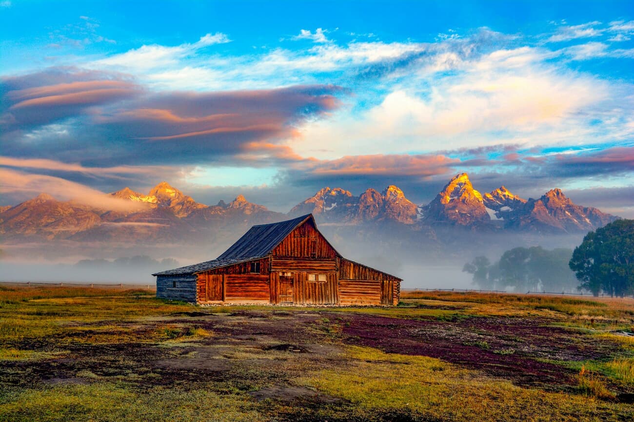 The Moulton Barn sits below the sawtooth line of the Tetons at sunrise in Grand Teton National Park, Wyoming