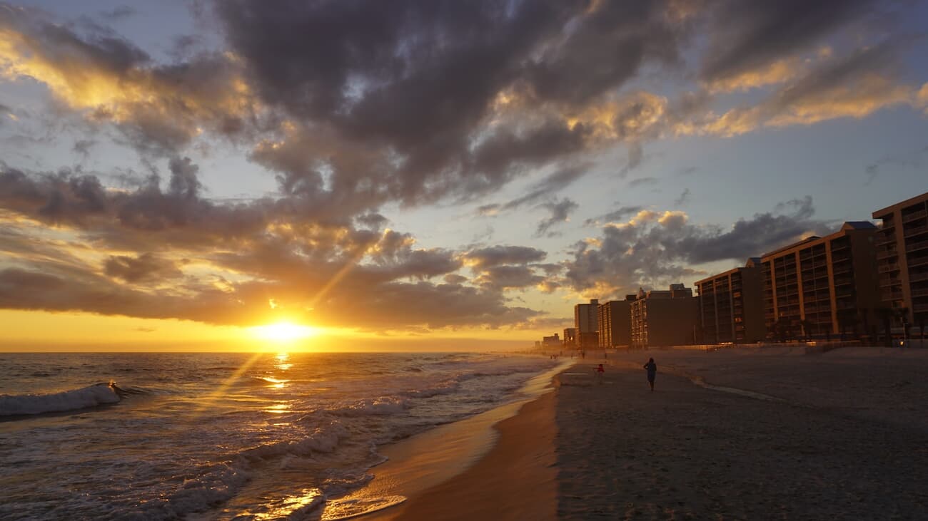The sun sets over the white-sand beachfront at Gulf Shores, Alabama
