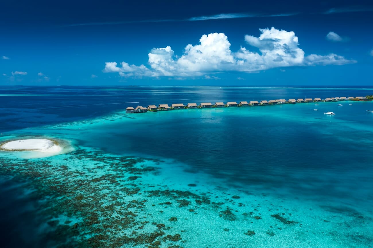 Overwater villas trace the edge of a turquoise atoll in the Maldives