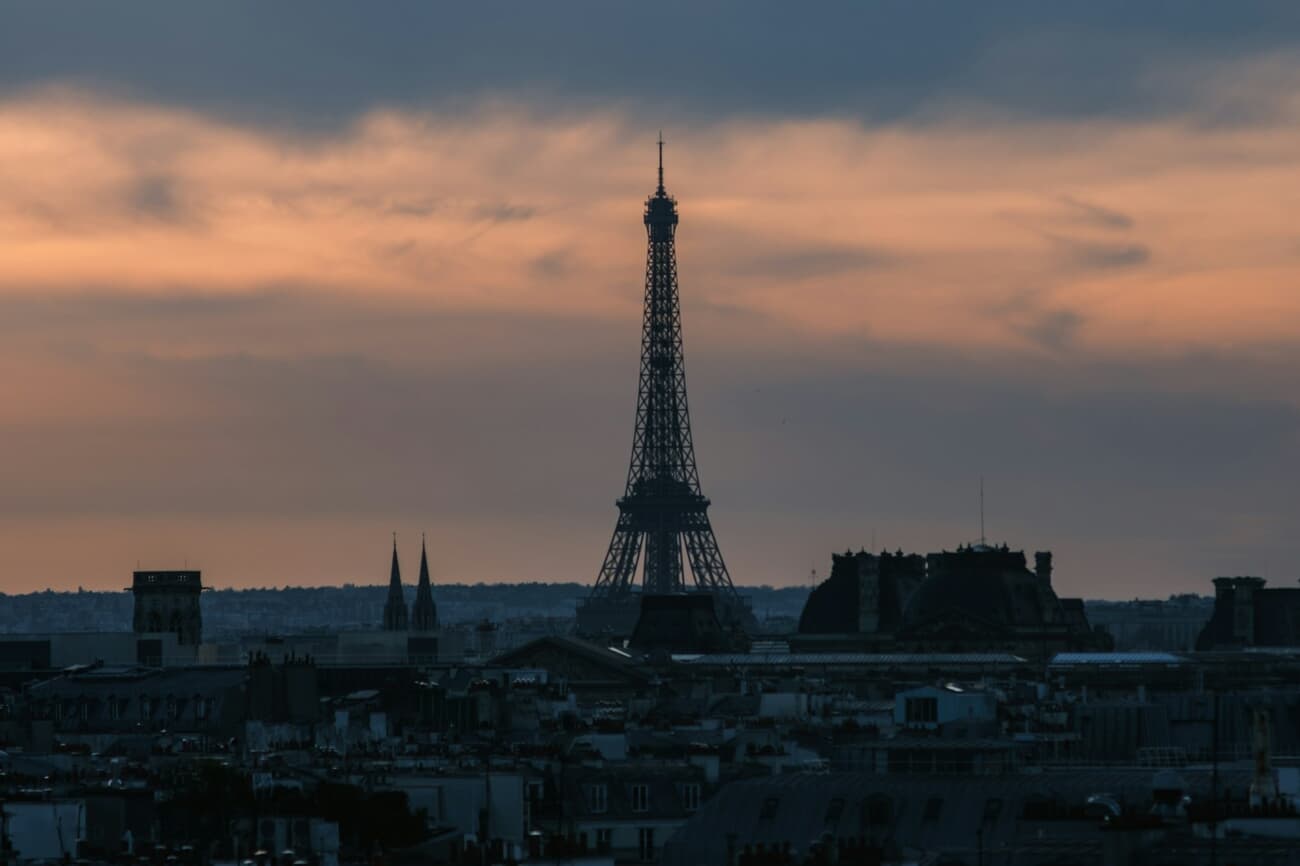 The Eiffel Tower stands over the Paris skyline at dusk