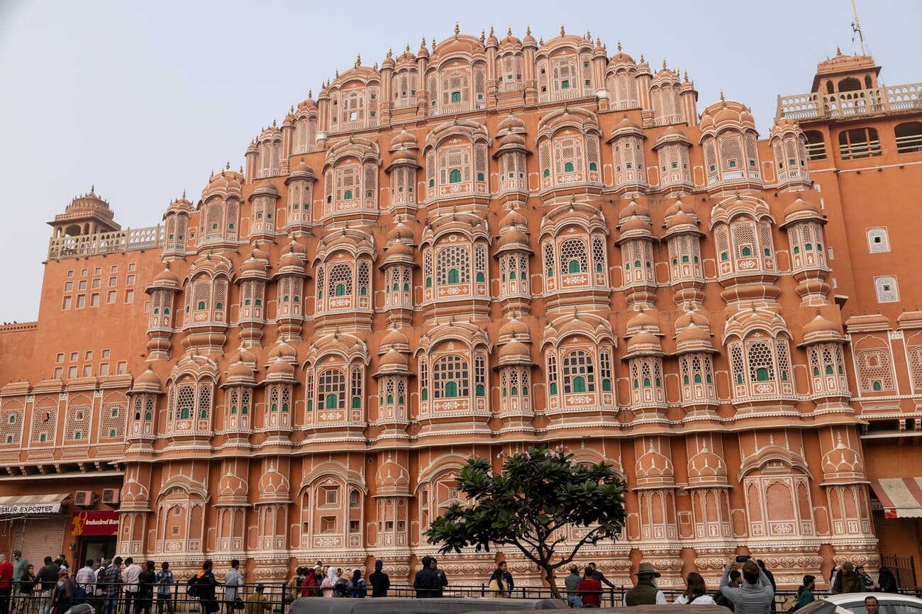 The pink sandstone windows of the Hawa Mahal rise over the street in Jaipur, Rajasthan