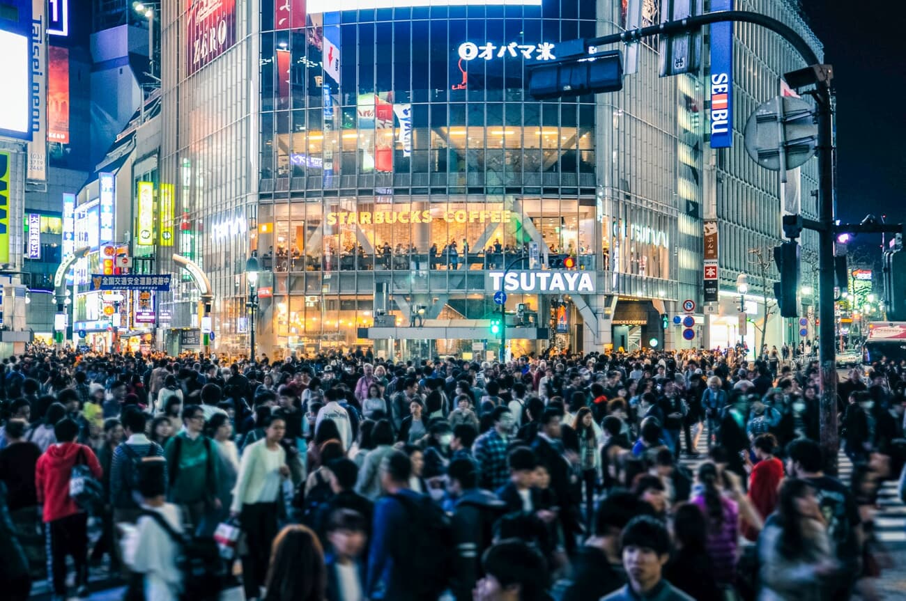 Crowds stream through the neon-lit Shibuya crossing in Tokyo, Japan