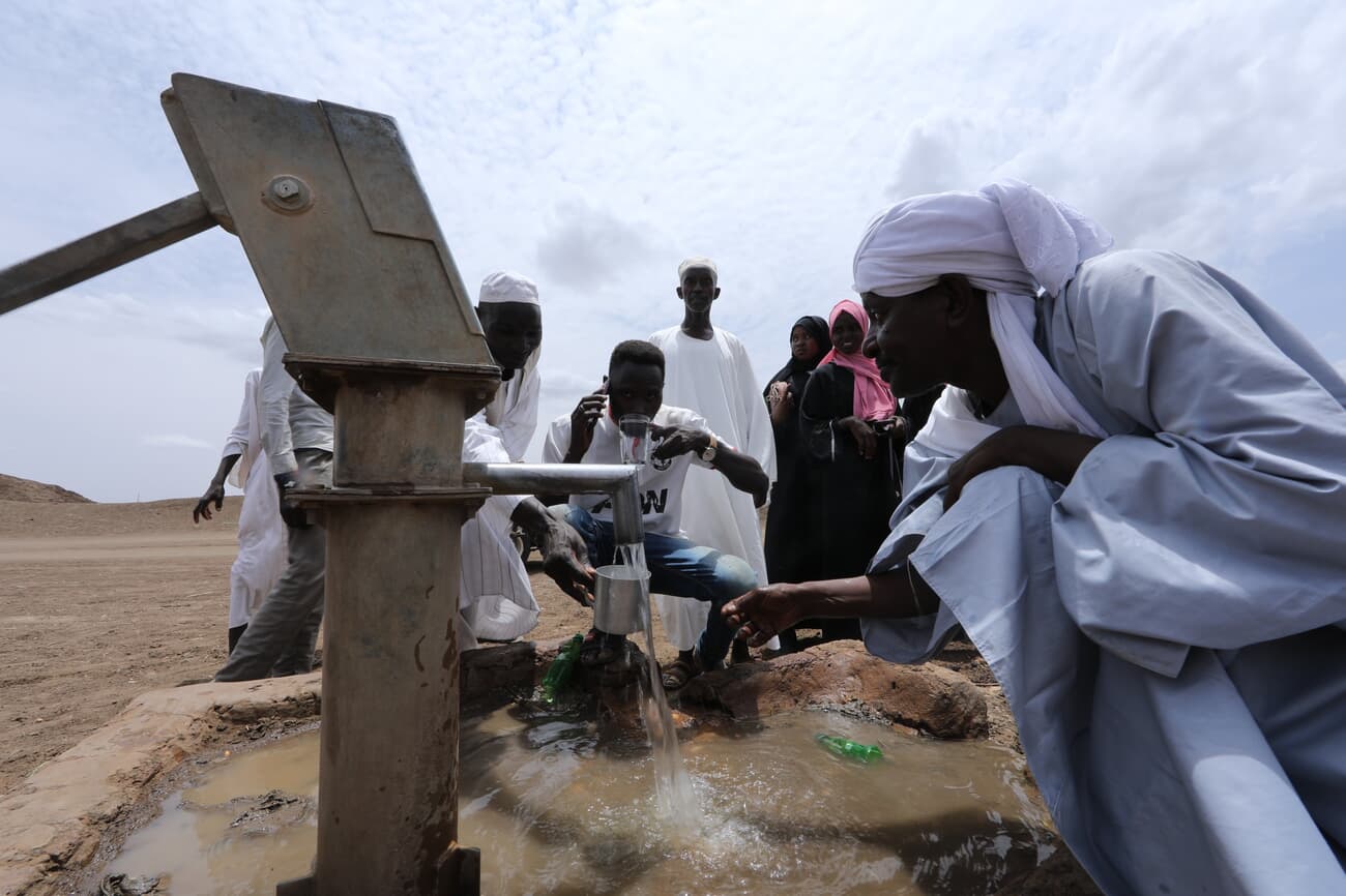 Villagers collecting water from a hand pump in Sudan
