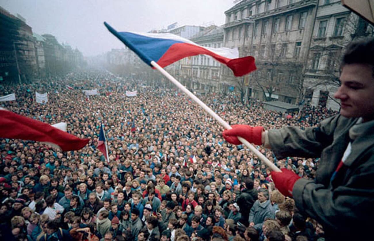Huge crowd in Prague's Wenceslas Square during the 1989 Velvet Revolution, a man waving the flag