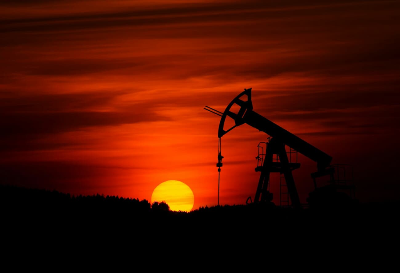 Oil pump jack silhouetted against an orange sunset