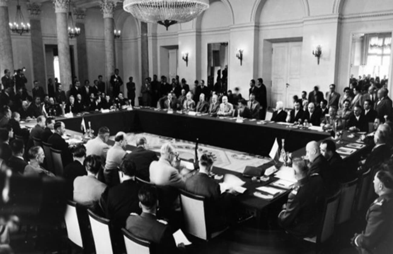 Black and white photograph of an Eastern Bloc conference with delegates around a large table