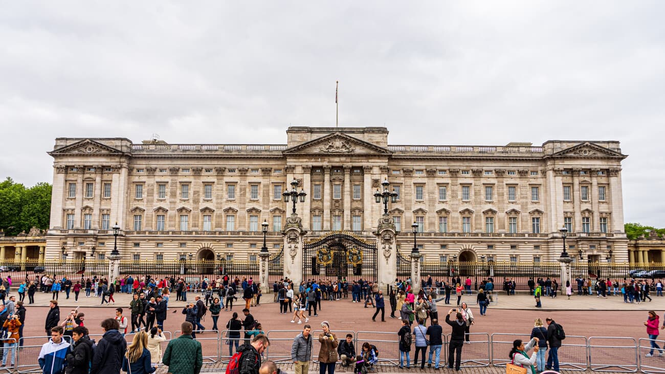 A crowd of people in front of Buckingham Palace on an overcast day.