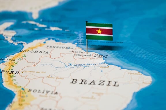 Flag pin pointing out the location of Suriname on the South America map