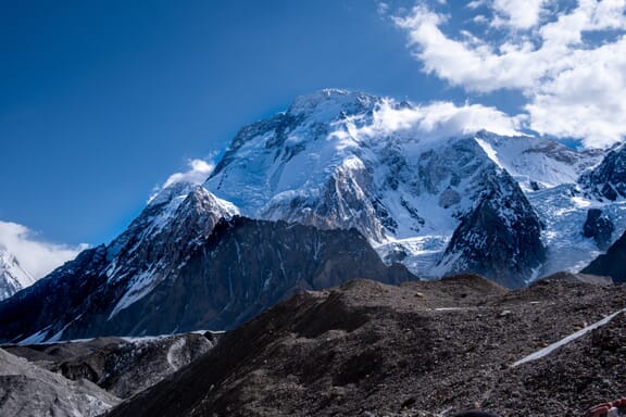 Small clouds hover around the summit of Broad Peak during an otherwise clear day. Small clouds hover around the summit of Broad Peak during an otherwise clear day.