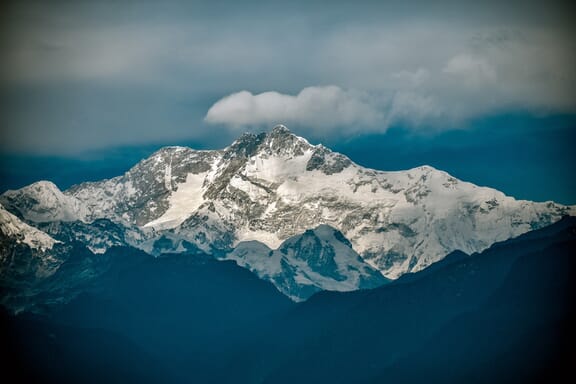 The snowy and rocky main peak of Kangchenjunga rises into the clouds between Nepal and India.