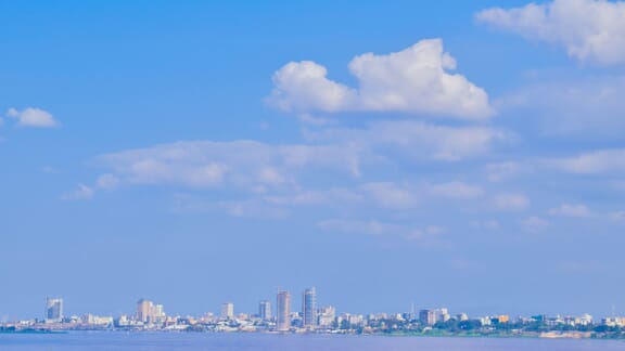 The skyline of Kinshasa can be seen under a blue sky across the water. The skyline of Kinshasa can be seen under a blue sky across the water.