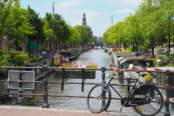 A bike sits on a bridge over a canal on a sunny day in Amsterdam, the capital of the Netherlands. A bike sits on a bridge over a canal on a sunny day in Amsterdam, the capital of the Netherlands.