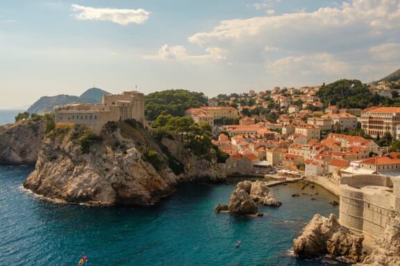 Red-roofed buildings sit near the water in Dubrovnik, Croatia. Red-roofed buildings sit near the water in Dubrovnik, Croatia.