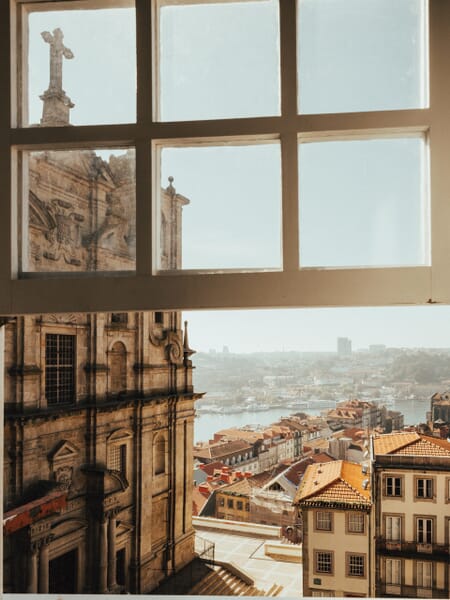 Part of the skyline of Porto, Portugal can be seen through an open window.