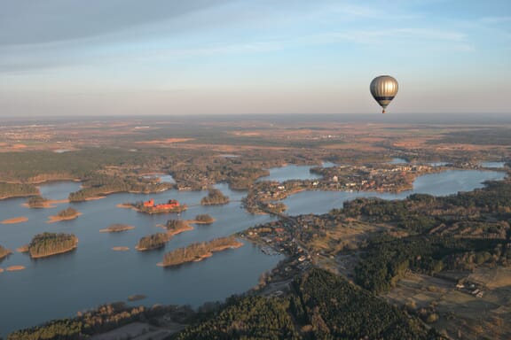 An aerial view of a hot air balloon floating over lakes in Trakai, Lithuania. An aerial view of a hot air balloon floating over lakes in Trakai, Lithuania.