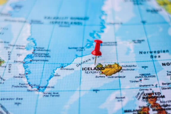 Pin pointing out the Iceland on a map.
