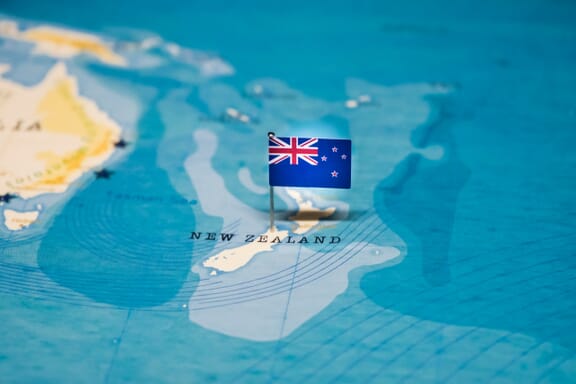 The New Zealand flag pointing out the location of New Zealand on the map.