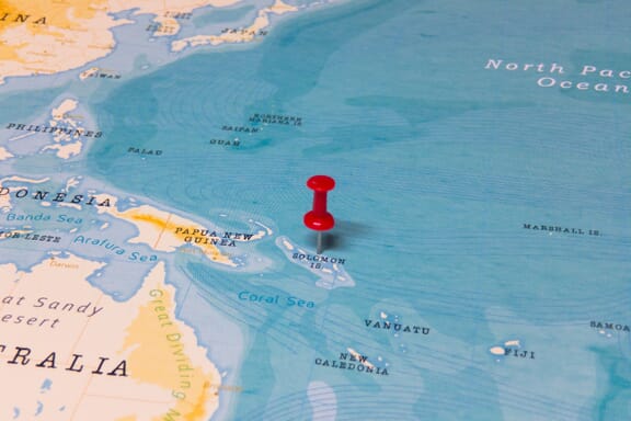 Pin pointing out the Solomon Islands on a map.