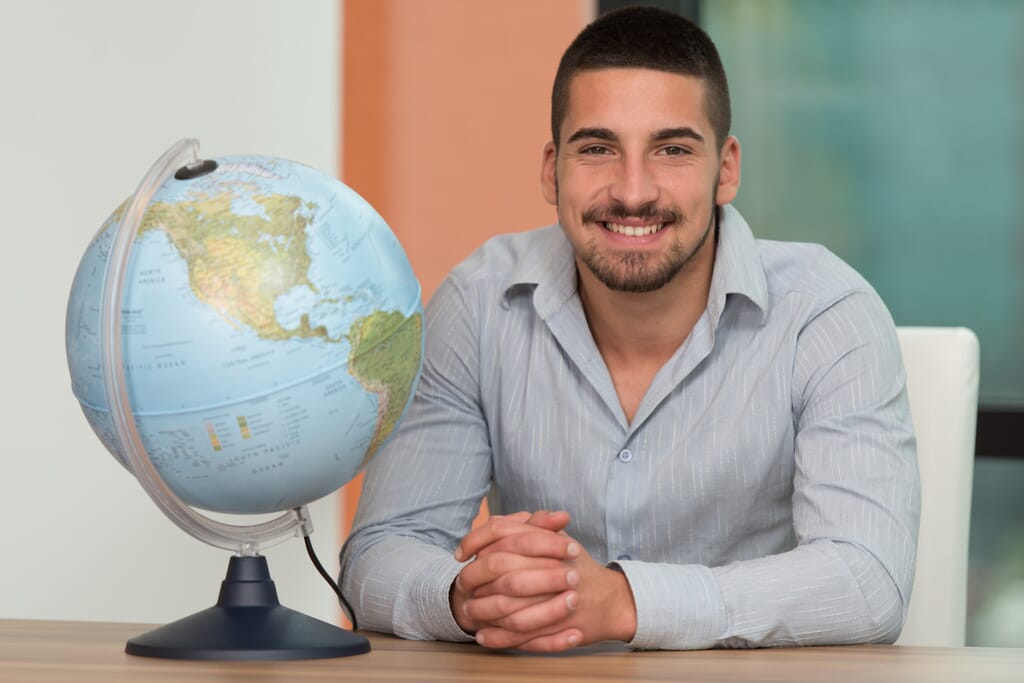 World Globe for Adults. Man sitting next to a globe.