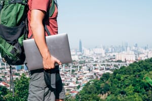 Digital nomad man traveling, showing city in the background.