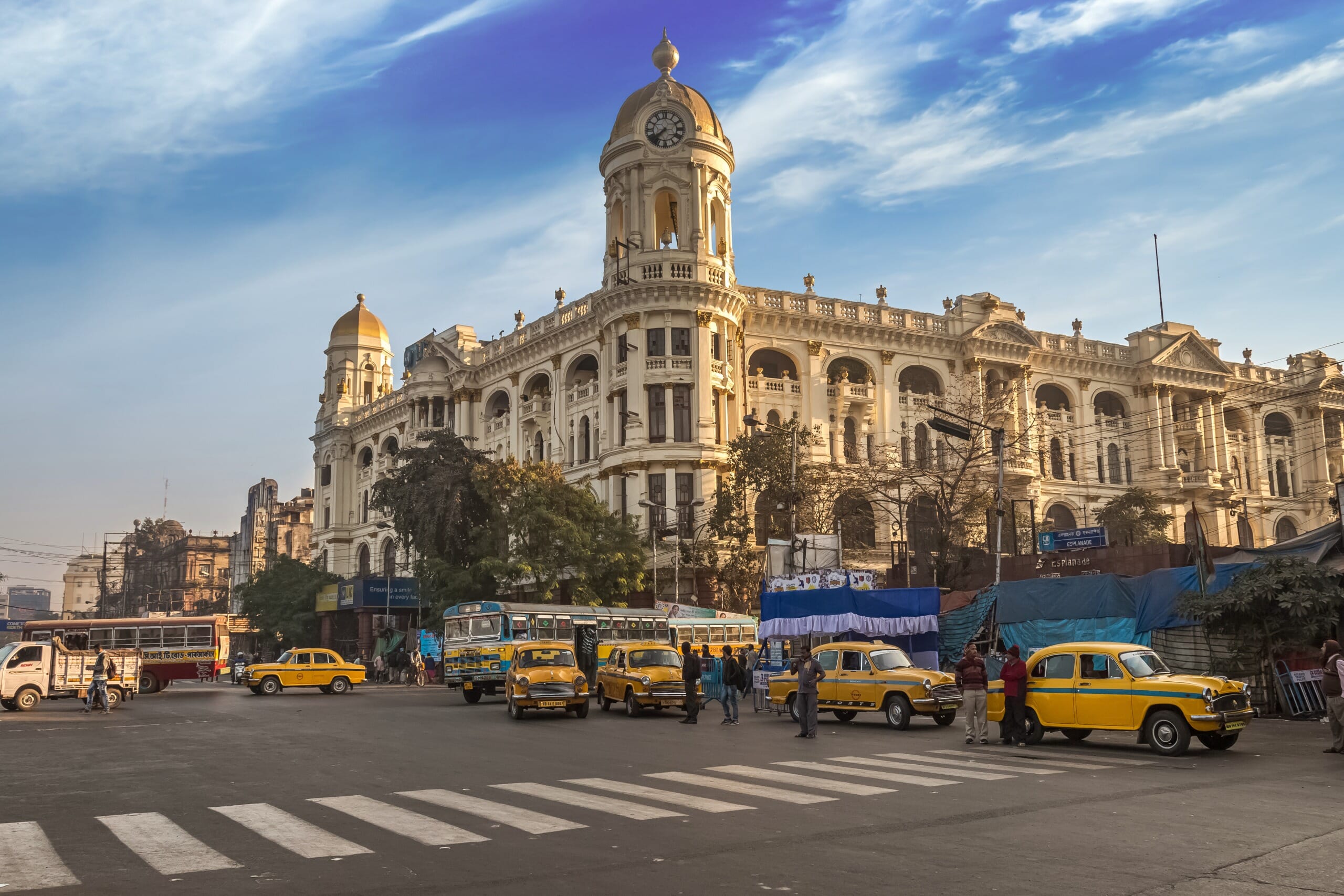 A street-level view of the Metropolitan Building in Kolkata, with yellow taxis in the foreground.