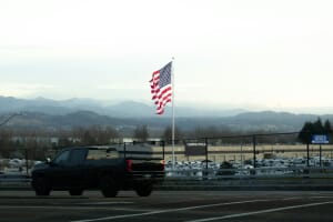 American flag waving on a road trip with mountains in the background, evoking the Memorial Day Weekend long-drive travel tradition